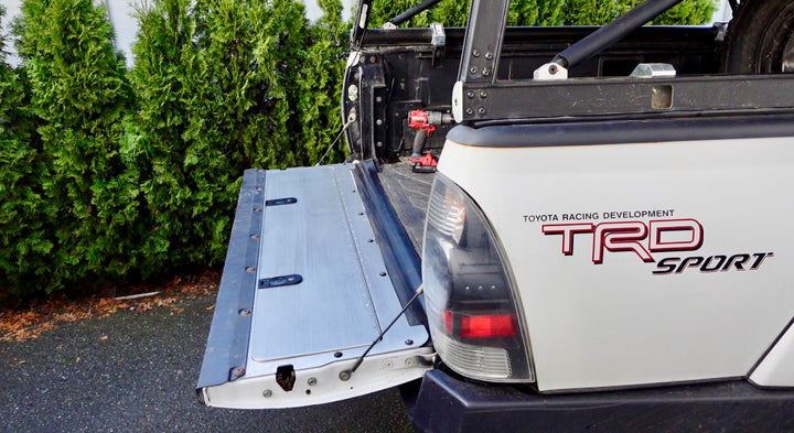 Open tailgate panel installed on a white Toyota Tacoma TRD Sport pickup truck, showcasing the BPF 2005-2015 Toyota Tacoma Tailgate Panel with powder coated finish and heavy duty construction.