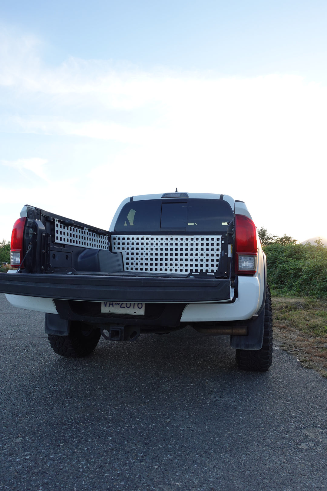 Rear view of a white truck with BPF 05-23 Tacoma bed Molle panels installed on the bed sides, showcasing durable metal storage panels designed for organization and overlanding gear.