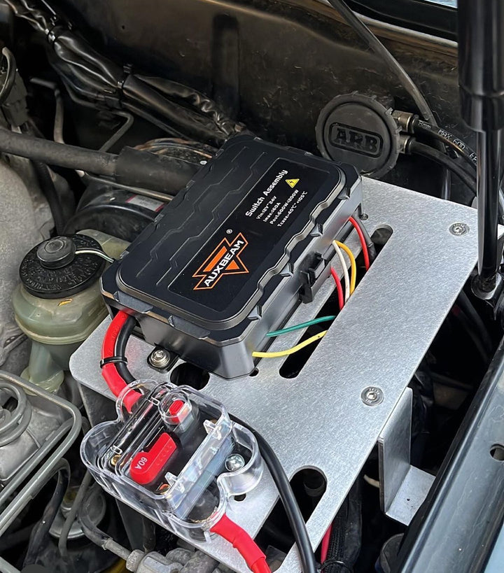 BPF 80 series Land cruiser Fuse block mount installed in engine bay, featuring a sturdy metal bracket holding a fuse block with multiple colored wires connected, showcasing rugged automotive accessory installation.