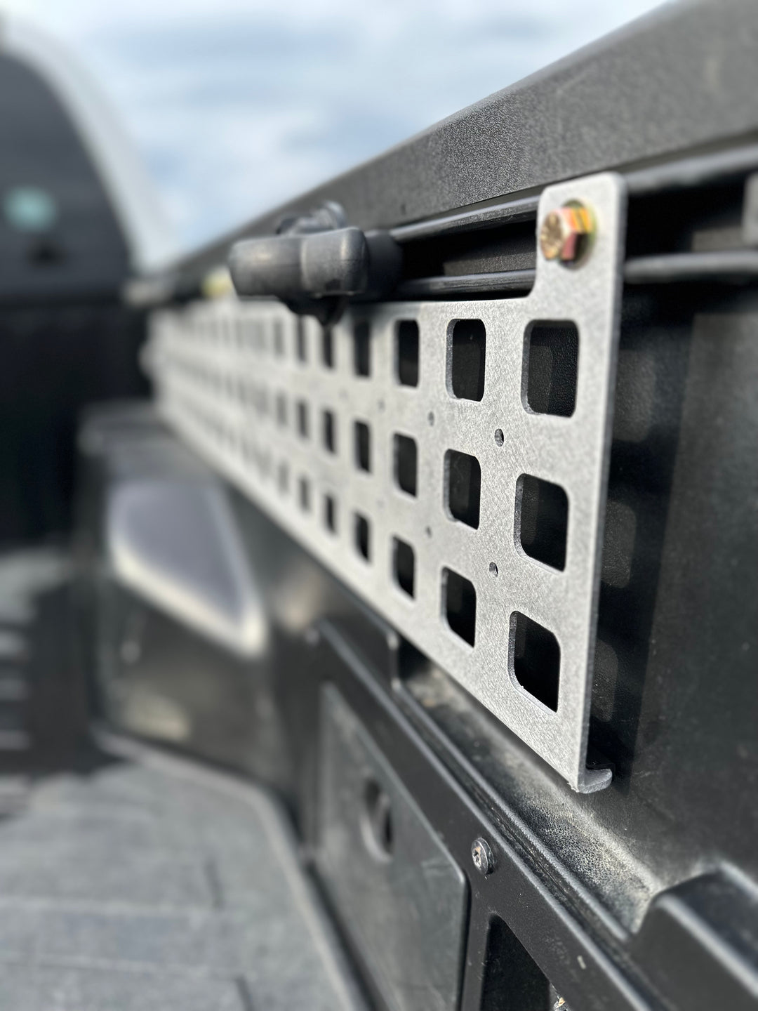 Close-up view of a powder-coated metal MOLLE panel securely mounted on a truck bed rail, showcasing the high-quality BPF 05-23 Tacoma bed Molle panels designed for durable and organized gear storage.