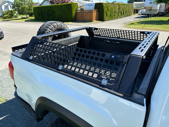 05-26 Tacoma Bed Rack fits 2nd,3rd and 4th gen Tacomas installed on a white truck bed with black powder-coated steel mesh and roof rack mounts for overlanding gear and storage panels.