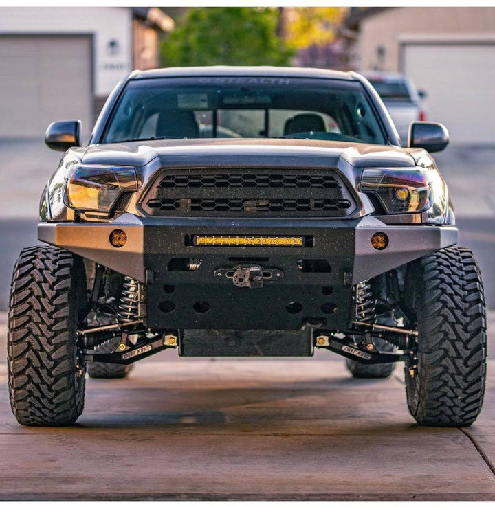 Front view of a rugged Toyota Tacoma equipped with a BPF 2012-2015 Toyota Tacoma Grill featuring a black hex mesh design, complemented by off-road tires and a heavy-duty bumper with integrated lights.