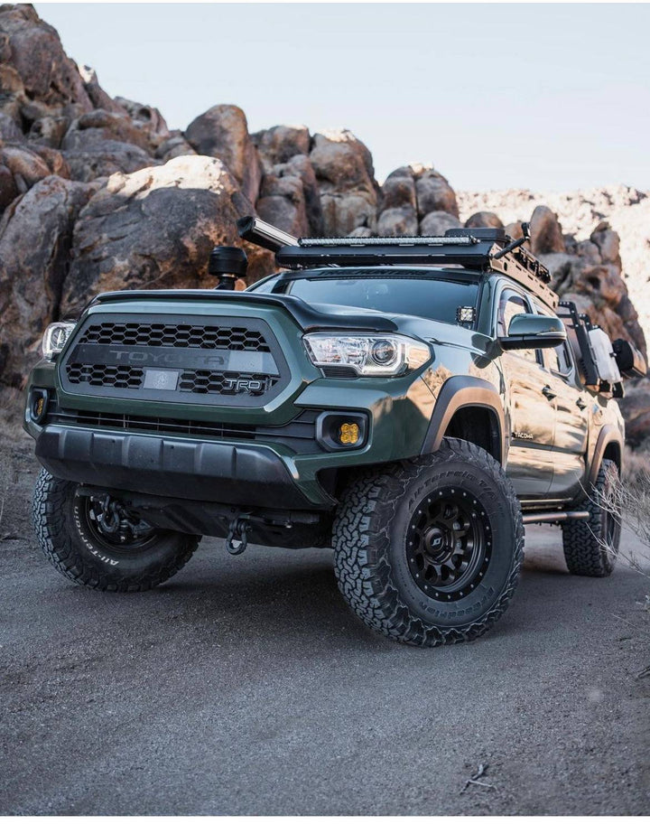 Off-road Toyota Tacoma equipped with a durable BPF 2016-2023 Toyota Tacoma Grill in matte black finish, showcasing rugged style and OEM fitment for enhanced front-end protection.